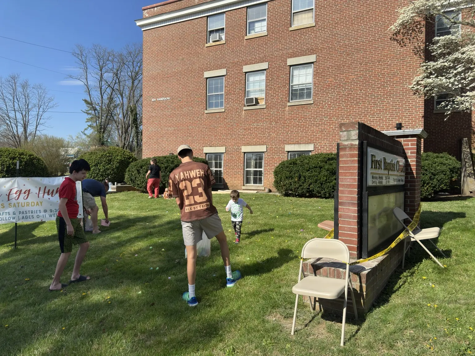 Children and adults gathering on the lawn beside First Baptist Church